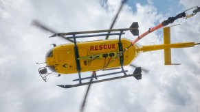 The yellow underside of a yellow "rescue" helicopter saving a man trapped behind a waterfall