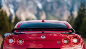 Red Nissan GT-R sports car, a mountain range visible in the background.