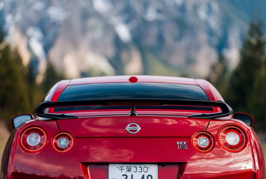 Red Nissan GT-R sports car, a mountain range visible in the background.