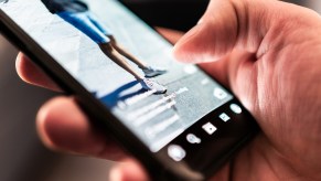 Police officer scrolling through TikTok while man is handcuffed in his police car on a hot day.