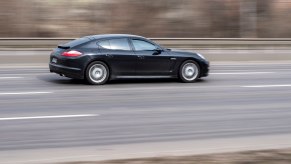 Black Porsche Panamera speeding along a highway in Europe