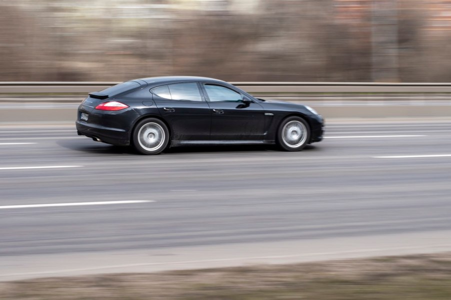 Black Porsche Panamera speeding along a highway in Europe