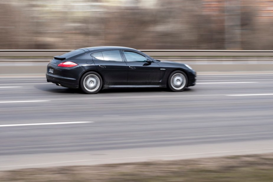 Black Porsche Panamera speeding along a highway in Europe