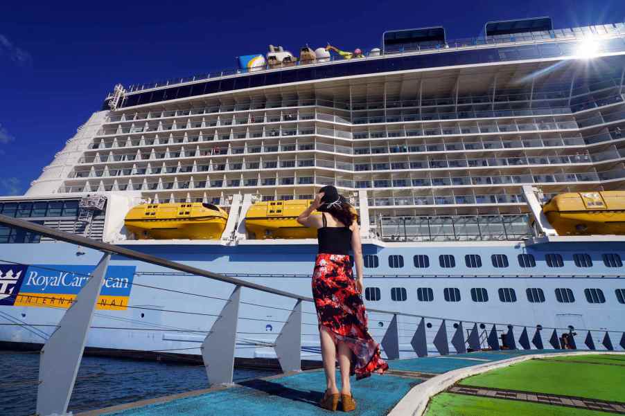 A woman standing looking at a Royal Caribbean cruise ship