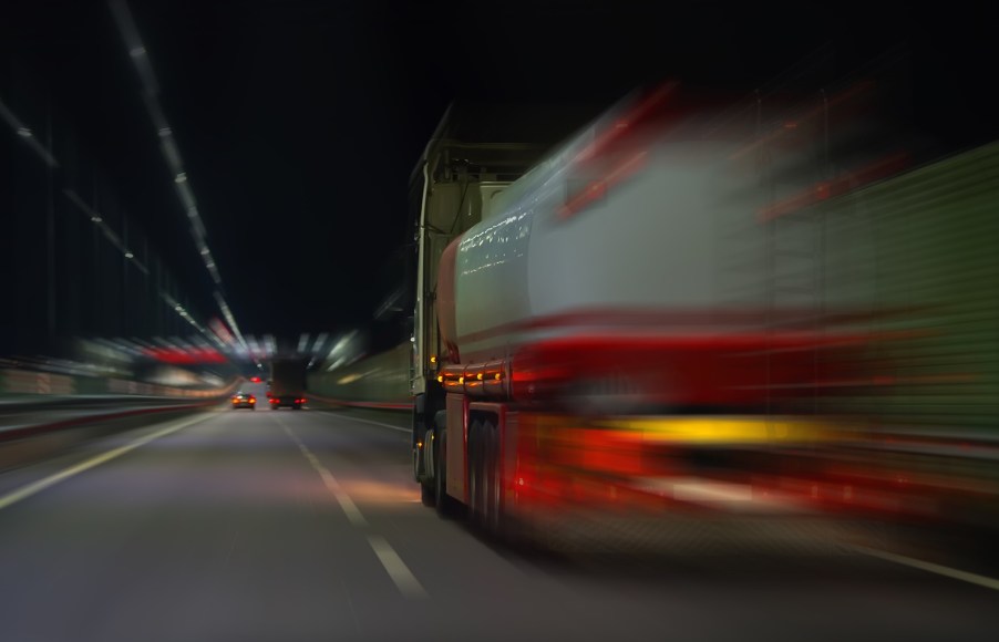White semi truck with a tanker trailer whizzing down the highway.