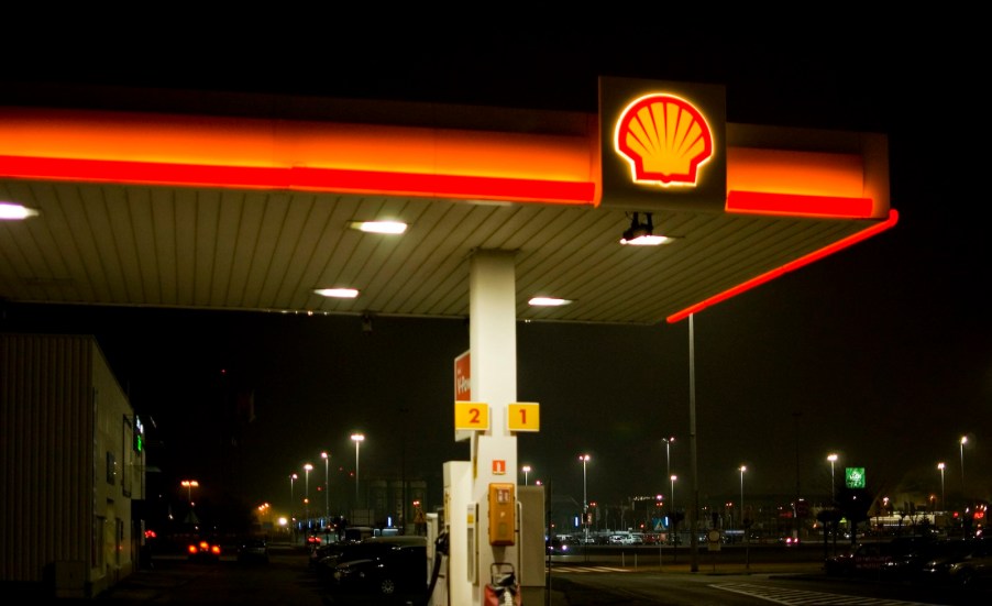 The Shell sign over a gas station at night.