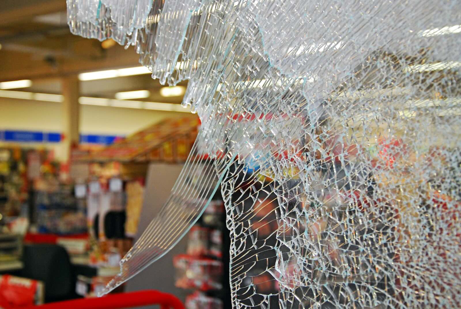 The smashed window at the front of a store from a robbery.