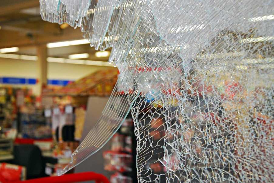The smashed window at the front of a store from a robbery.