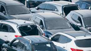 Dusty cars, trucks, and crossovers parked bumper-to-bumper.
