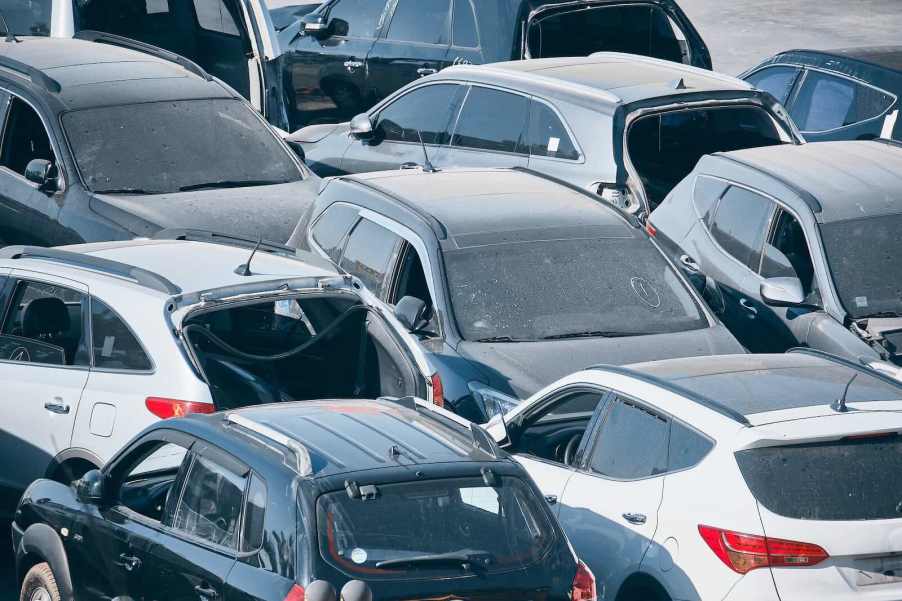 Dusty cars, trucks, and crossovers parked bumper-to-bumper.