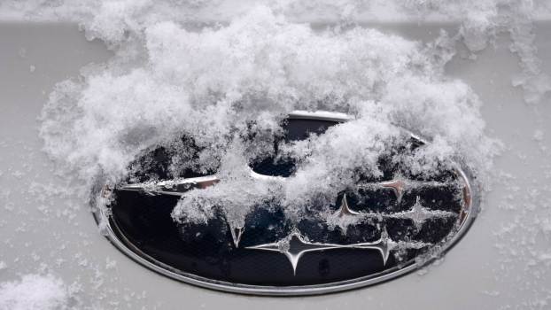 Snow collecting on the logo of a Subaru car.