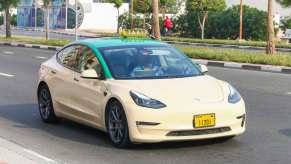 Tan colored Tesla Model 3 taxi driving the streets of Dubai