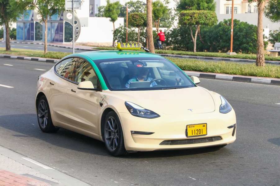 Tan colored Tesla Model 3 taxi driving the streets of Dubai