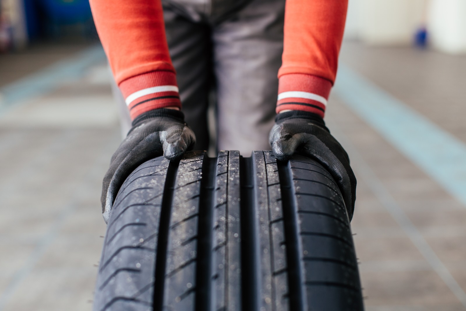 Hands of a man rolling a tire into a shop for replacement