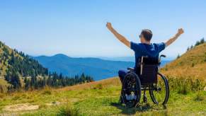 Wheelchair-bound main raises his arms in triumph on the top of a mountain in Wales.