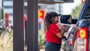 A Chick-fil-A employee taking drive-thru orders with an iPad