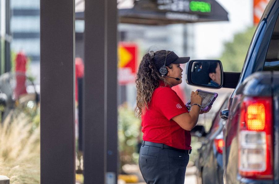 A Chick-fil-A employee taking drive-thru orders with an iPad