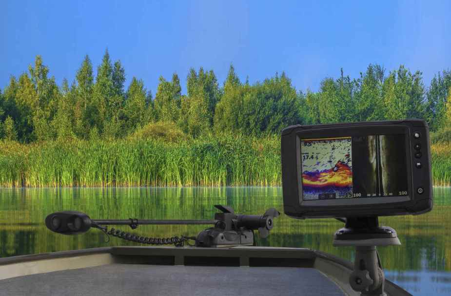 A boat on a water with lush greenery in background and close view of fishing sonar tool in foreground