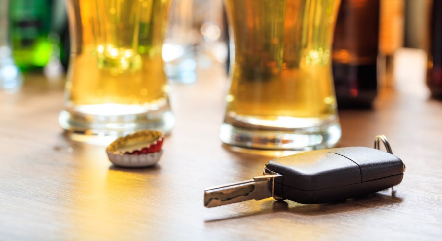 Two glasses of beer on a bar counter next to a set of car keys