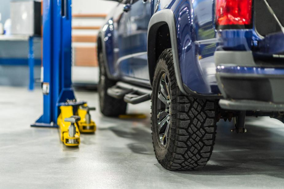 A pickup truck in lower left rear view parked in a car repair shop bay