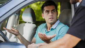 A driver holding their hands out in confusion at a police officer, depiction of a wrongful DUI