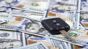A car key fob laying on a spread of $100 bills