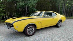A yellow 1969 Oldsmobile 442 parked on gravel in left front angle view