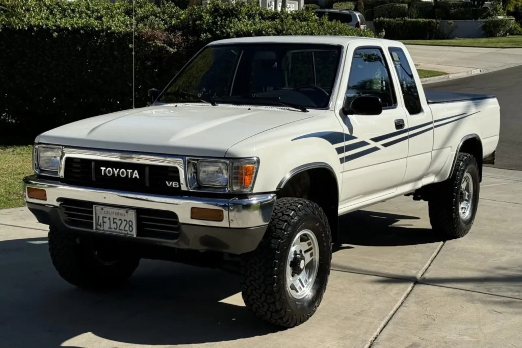 A white 1991 Toyota Pickup parked in a cement driveway in left front angle view