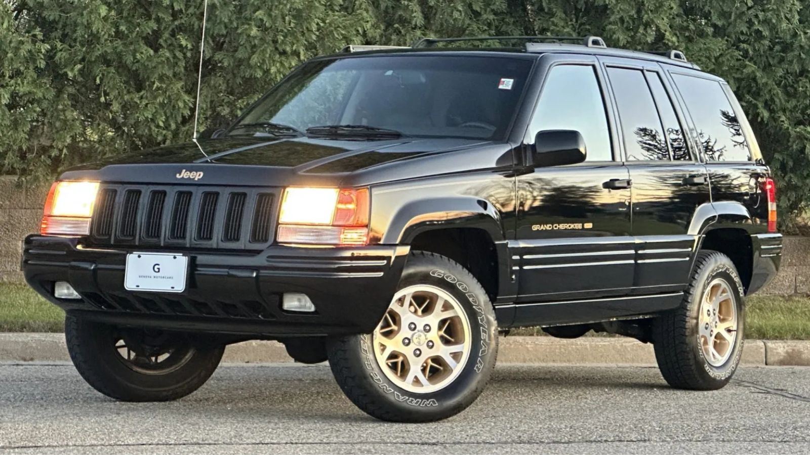 A black 1996 Jeep Grand Cherokee Limited parked in left front angle view with headlights on