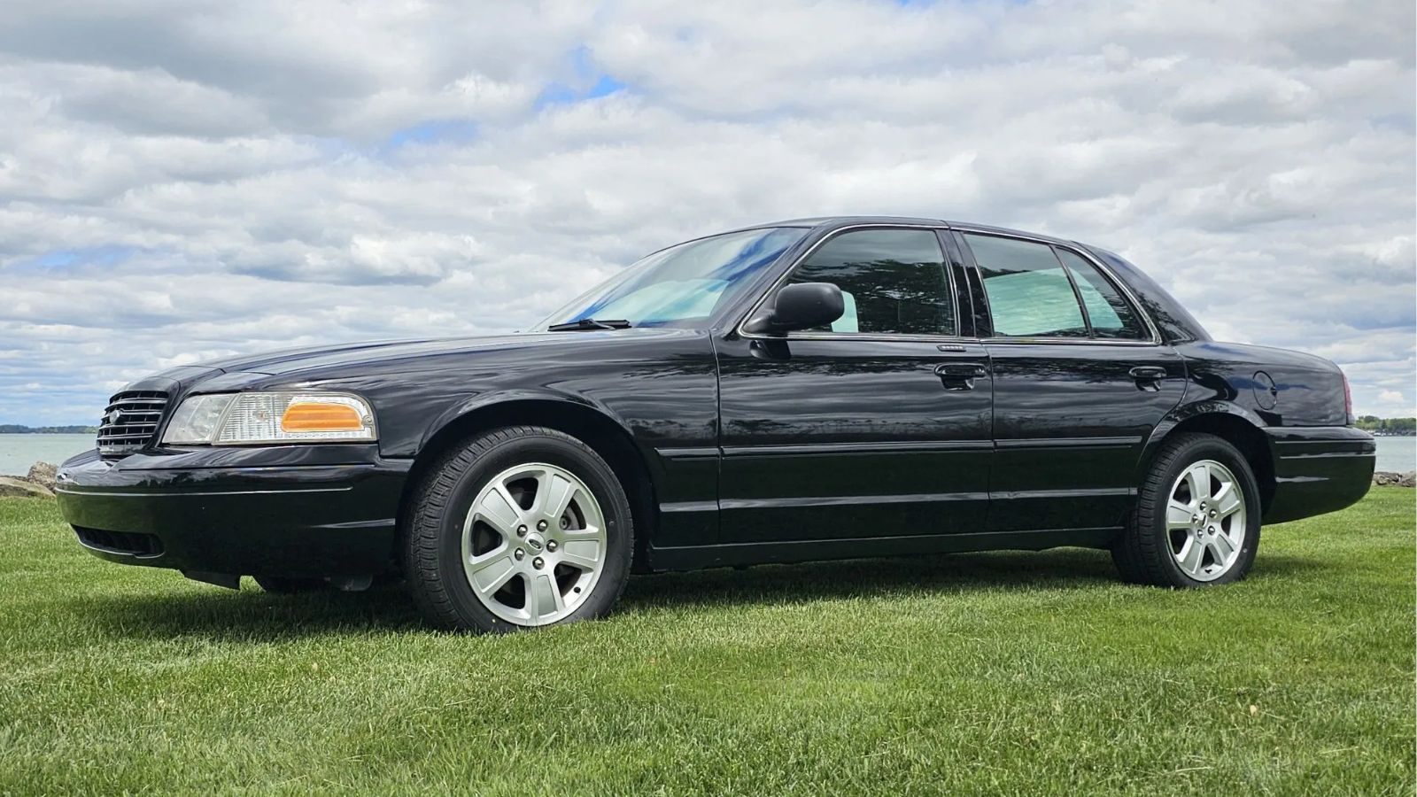 A black 2006 Ford Crown Victoria parked on grass in low left side view
