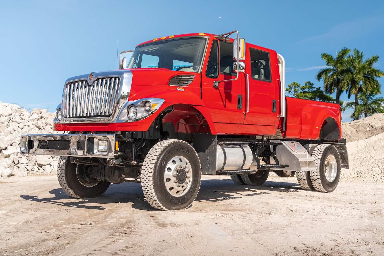 The front of a custom pickup truck built on a red International Harvester, palm trees visible in the background.