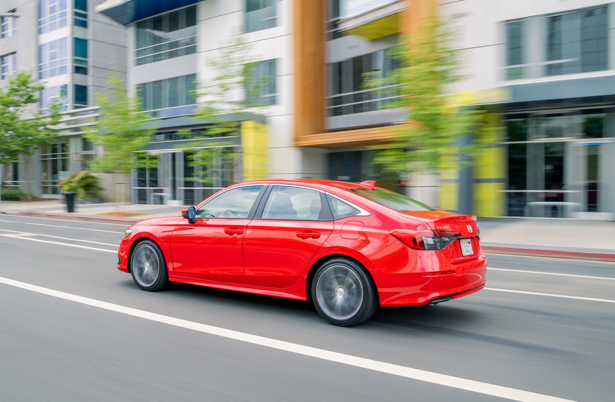 A red 2022 Honda Civic driving in left rear angle view