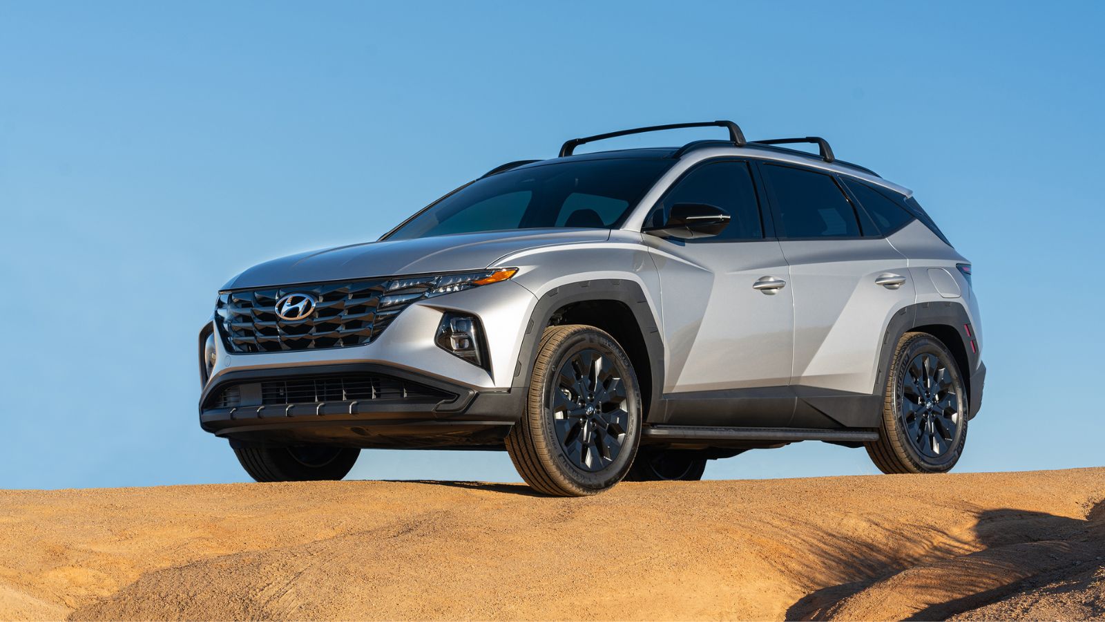 A silver 2022 Hyundai Tucson parked on a sand dune in left front angle view