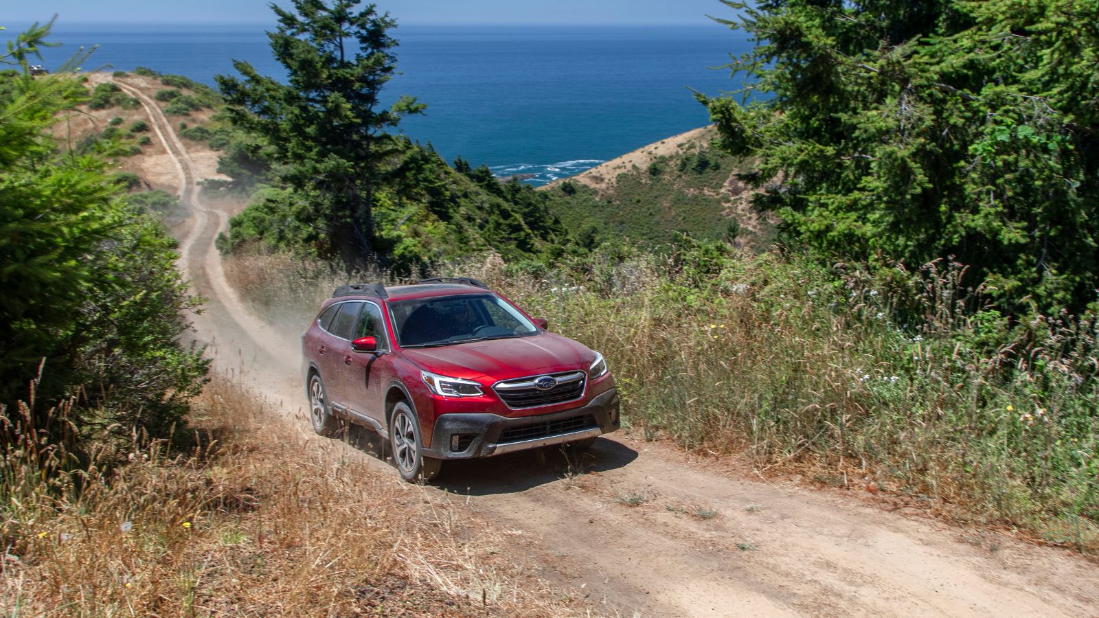 A red 2022 Subaru Outback driving on a dirt road