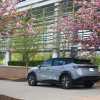 A 2025 Nissan Ariya parked next to cherry blossoms.