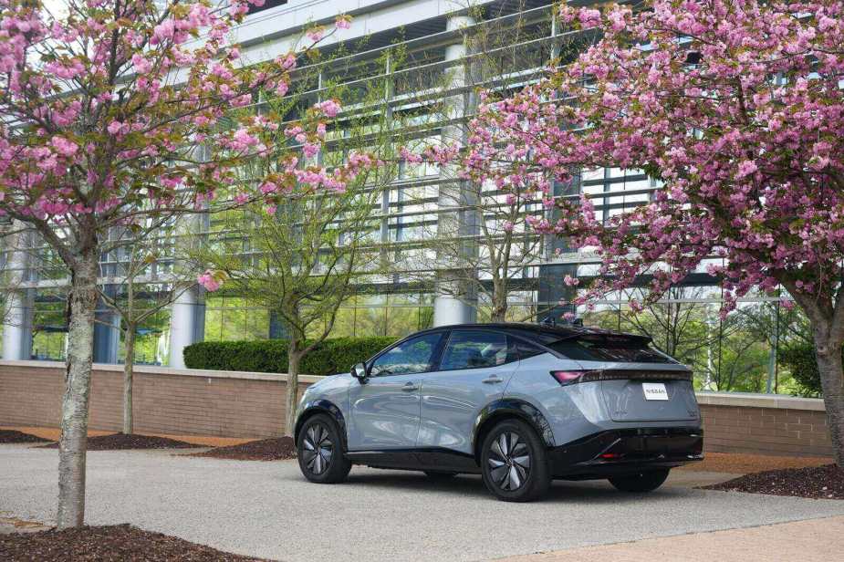 A 2025 Nissan Ariya parked next to cherry blossoms.