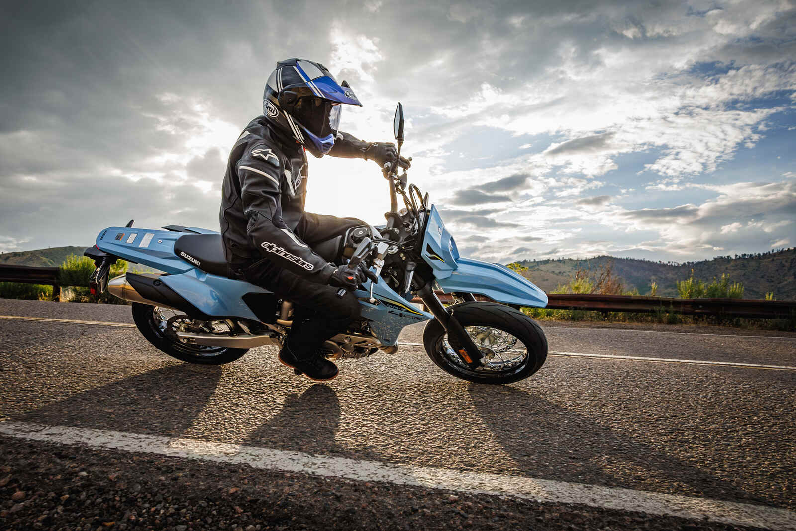 A male rider on a light blue 2025 Suzuki DR-Z400SM motorcycle