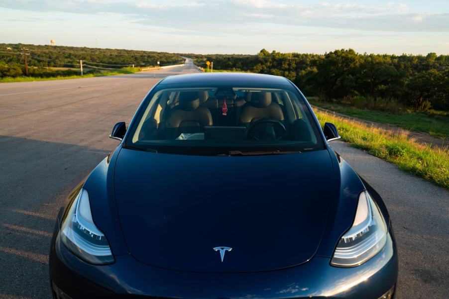 Black Tesla Model 3 with body in the front trunk has been abandoned on a country road.