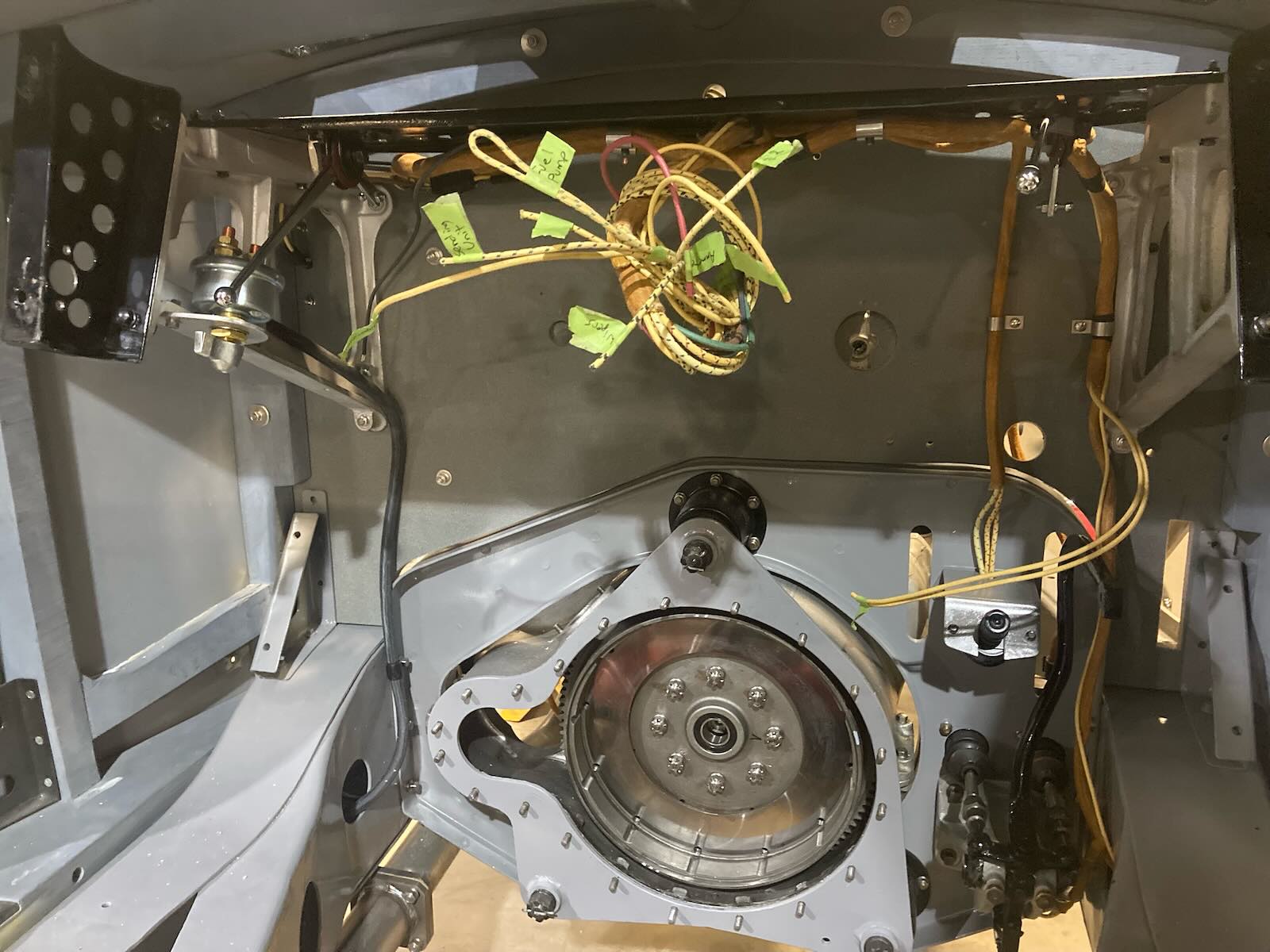 Transmission of a vintage Bugatti grand touring car undergoing restoration, a garage visible in the background.
