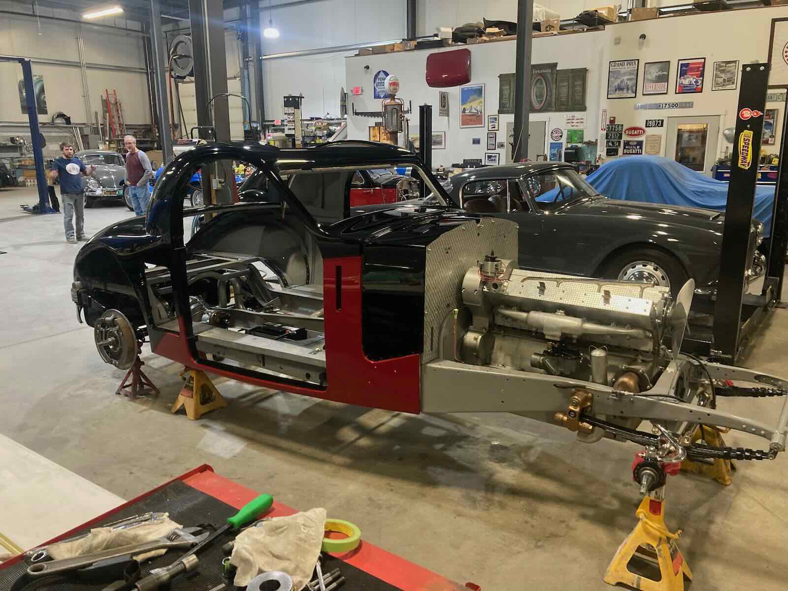 Vintage Bugatti grand touring car undergoing restoration, a garage visible in the background.