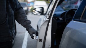 Hands of a car thief opening a vehicle door.
