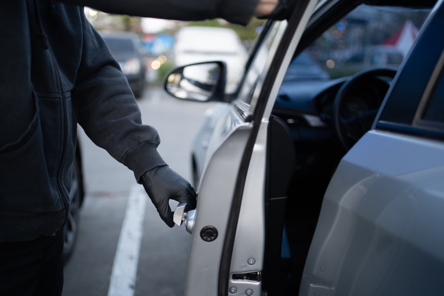 Hands of a car thief opening a vehicle door.