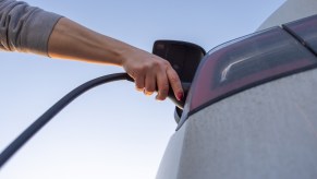 Woman's hand plugging in a Nissan Leaf, the USA's cheapest EV