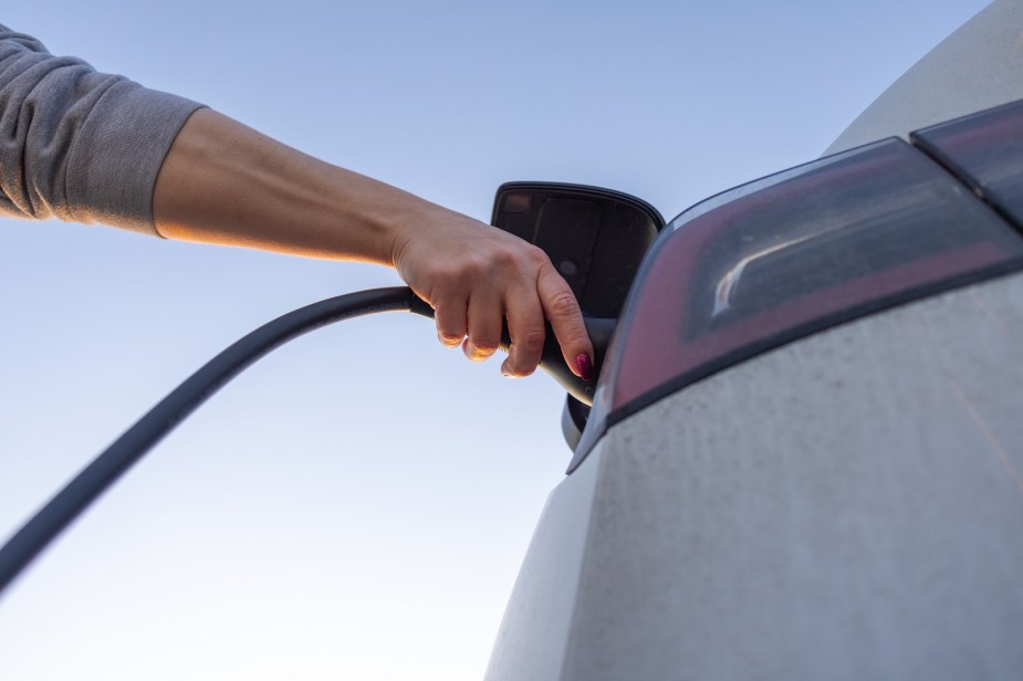 Woman's hand plugging in a Nissan Leaf, the USA's cheapest EV