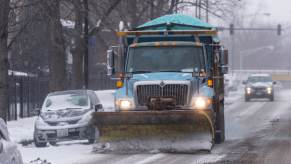 Light blue Chicago department of streets and sanitation plow truck on a city street.