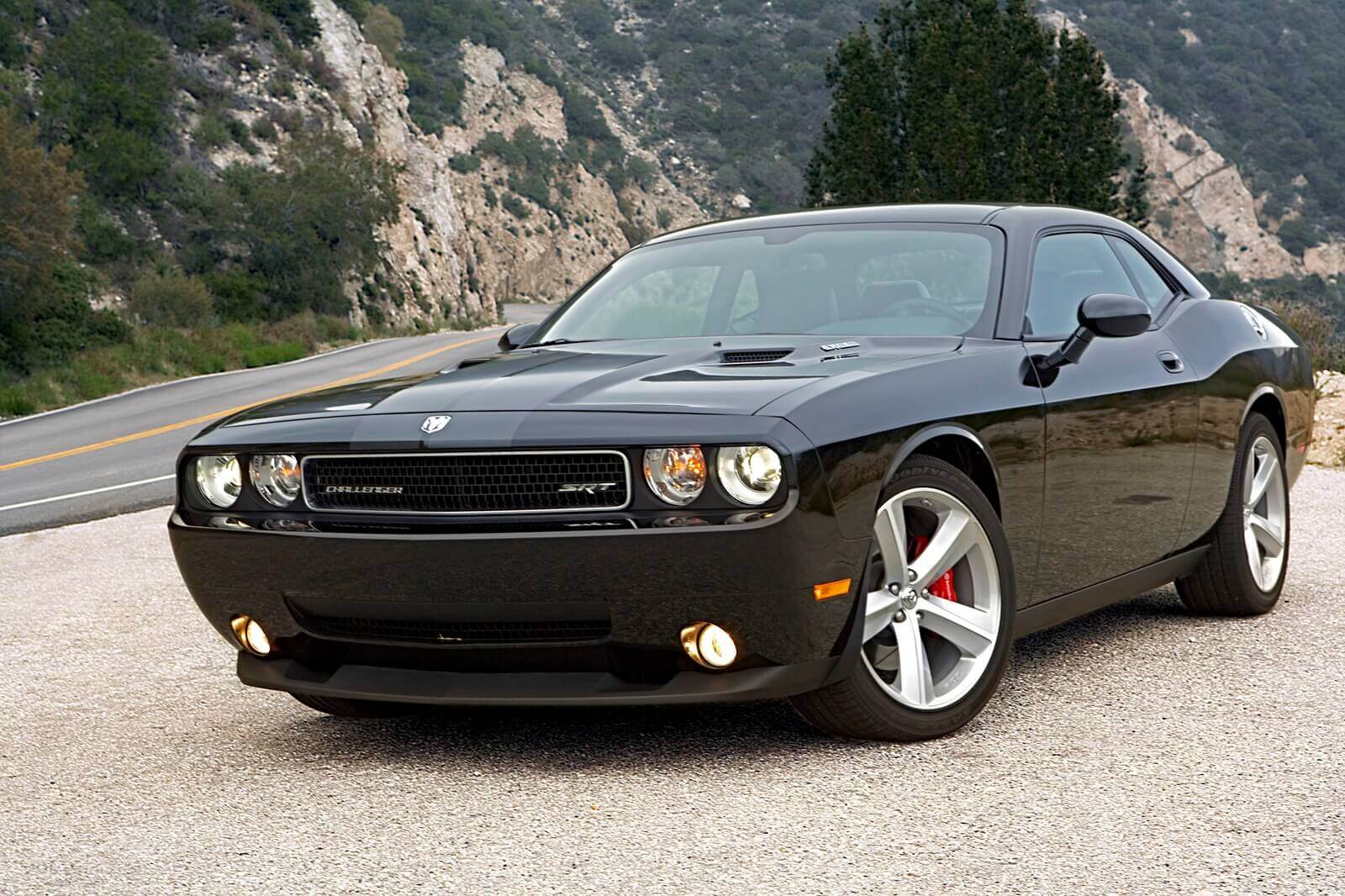 A black Dodge Challenger SRT8 parked next to a canyon corner.