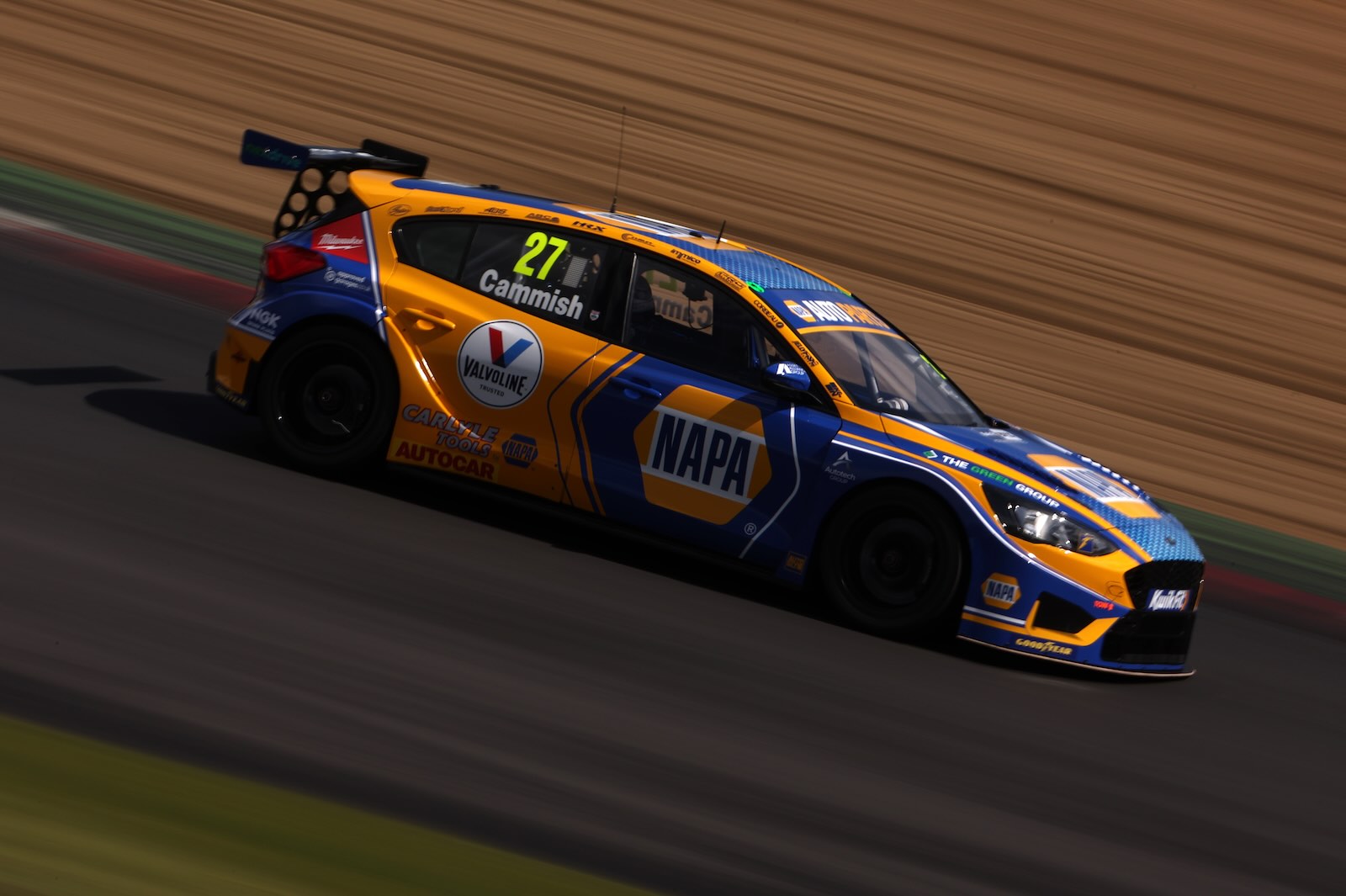 Modified blue and orange Ford Focus ST race car drives down a track, the background a blur.