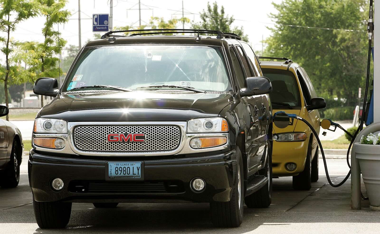 Black GMC Yukon taxi SUV parked at a gasoline pump.