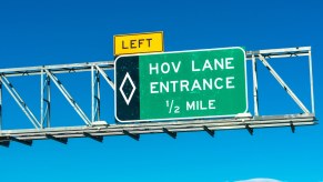 Green sign for the entrance to an HOV carpool lane which solo EV drivers can no longer use.