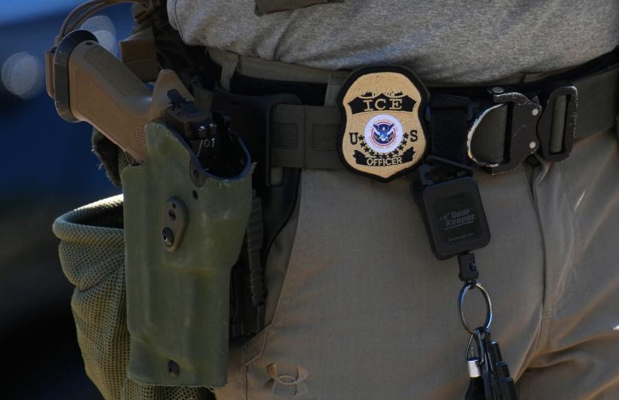 The gun and badge on the belt of an ICE officer